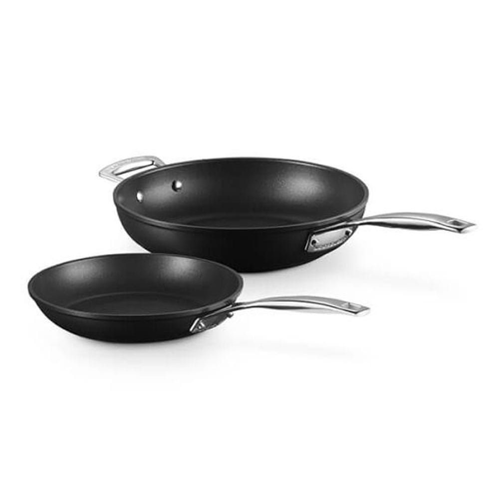 Two black frying pans with silver handles on a white background