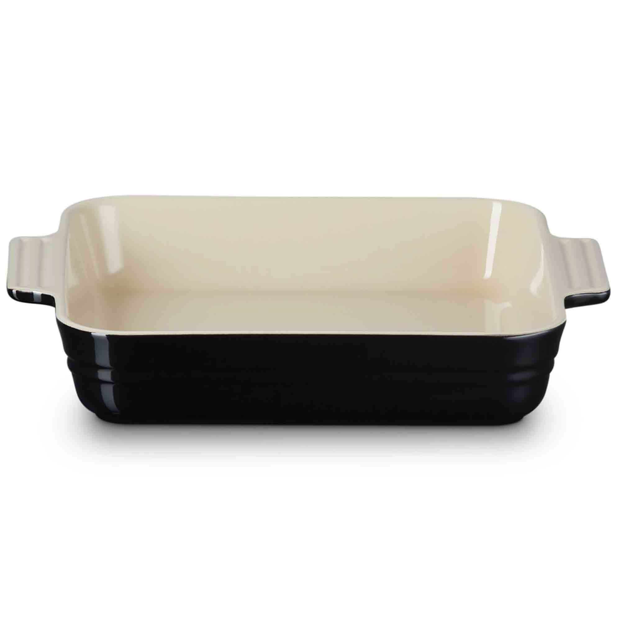 Baking dish with black base and cream-colored top on a white background