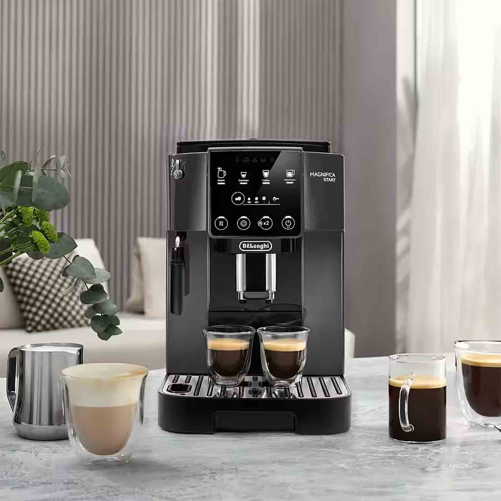 Black De'Longhi ECAM22022GB coffee machine on a table with glasses of coffee in a home setting.
