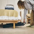 Person putting a clothes drier under a bed to store it