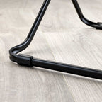 Close-up of a black metal clothes drier leg on a wooden floor