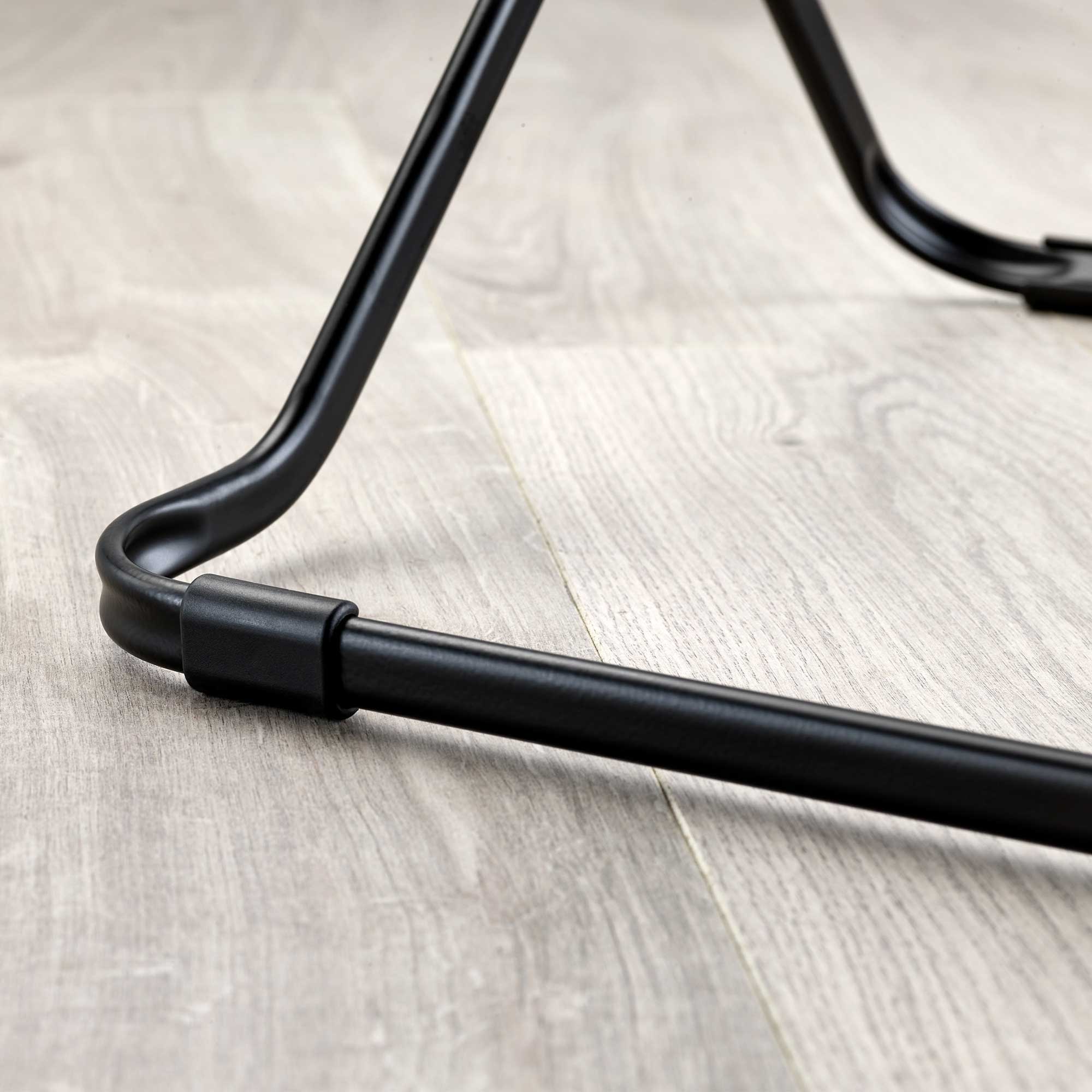 Close-up of a black metal clothes drier leg on a wooden floor