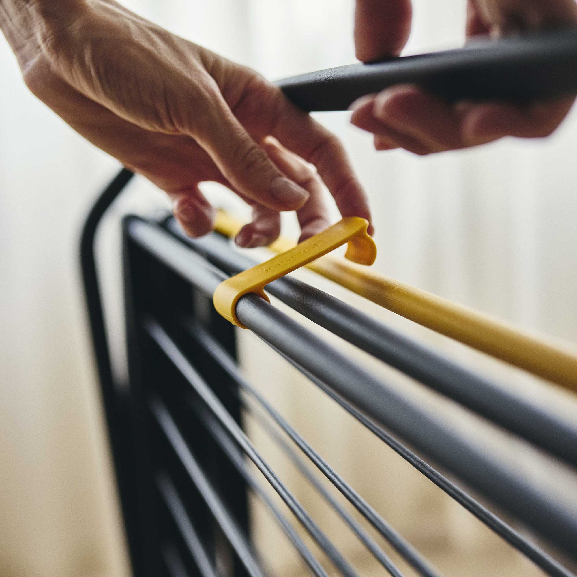Close-up of a hand putting a yellow clip over black and yellow bars