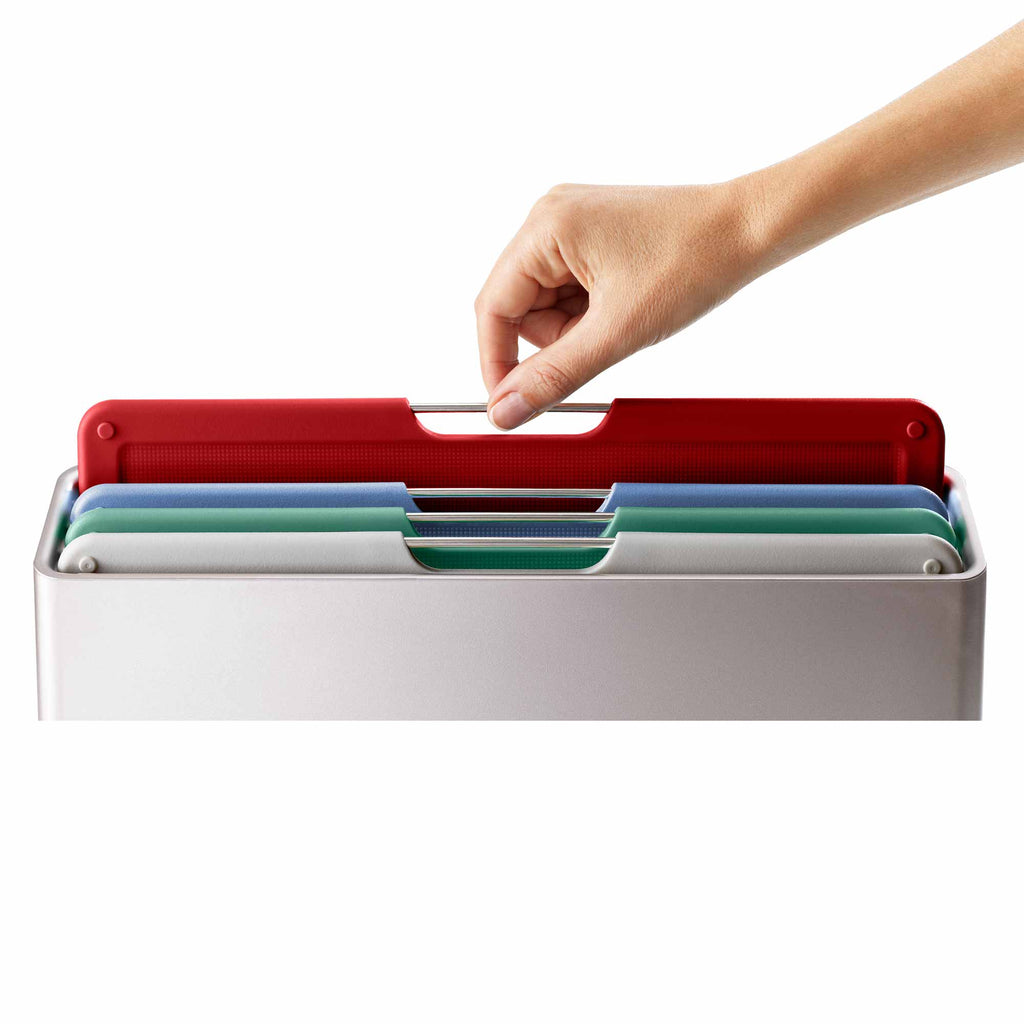Hand removing a red chopping board from a chopping board set on a white background