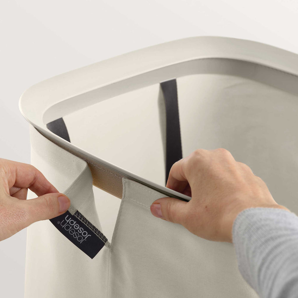 Person holding the top of a laundry basket with a detachable bag