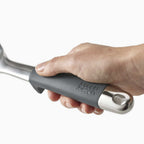 Hand holding a kitchen tool with 'Joseph Joseph' branding on a white background