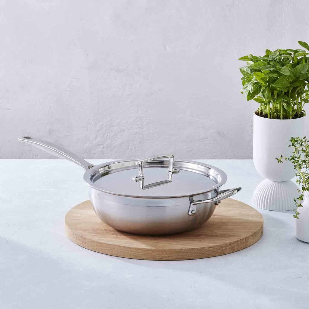Le Creuset 3-ply Stainless Steel Non-Stick Chef's Pan with Lid and Helper Handle on wooden board