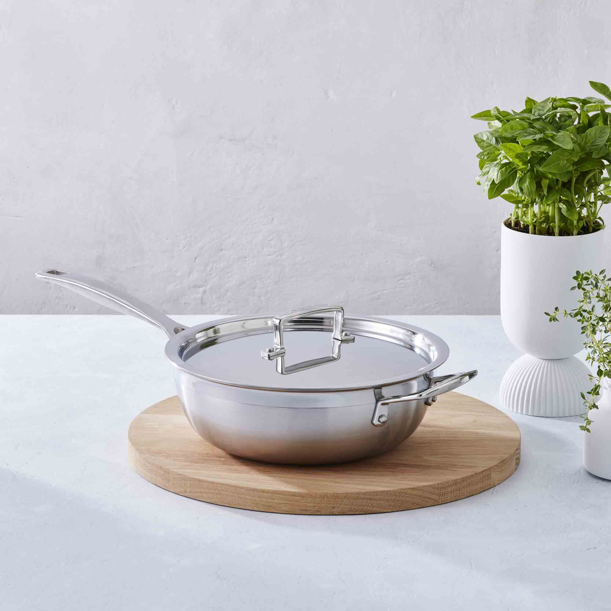 Le Creuset 3-ply Stainless Steel Non-Stick Chef's Pan with Lid and Helper Handle on wooden board