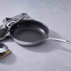 Le Creuset 3-ply Stainless Steel Non-Stick Frying Pan with Helper Handle on grey background with grey cloth