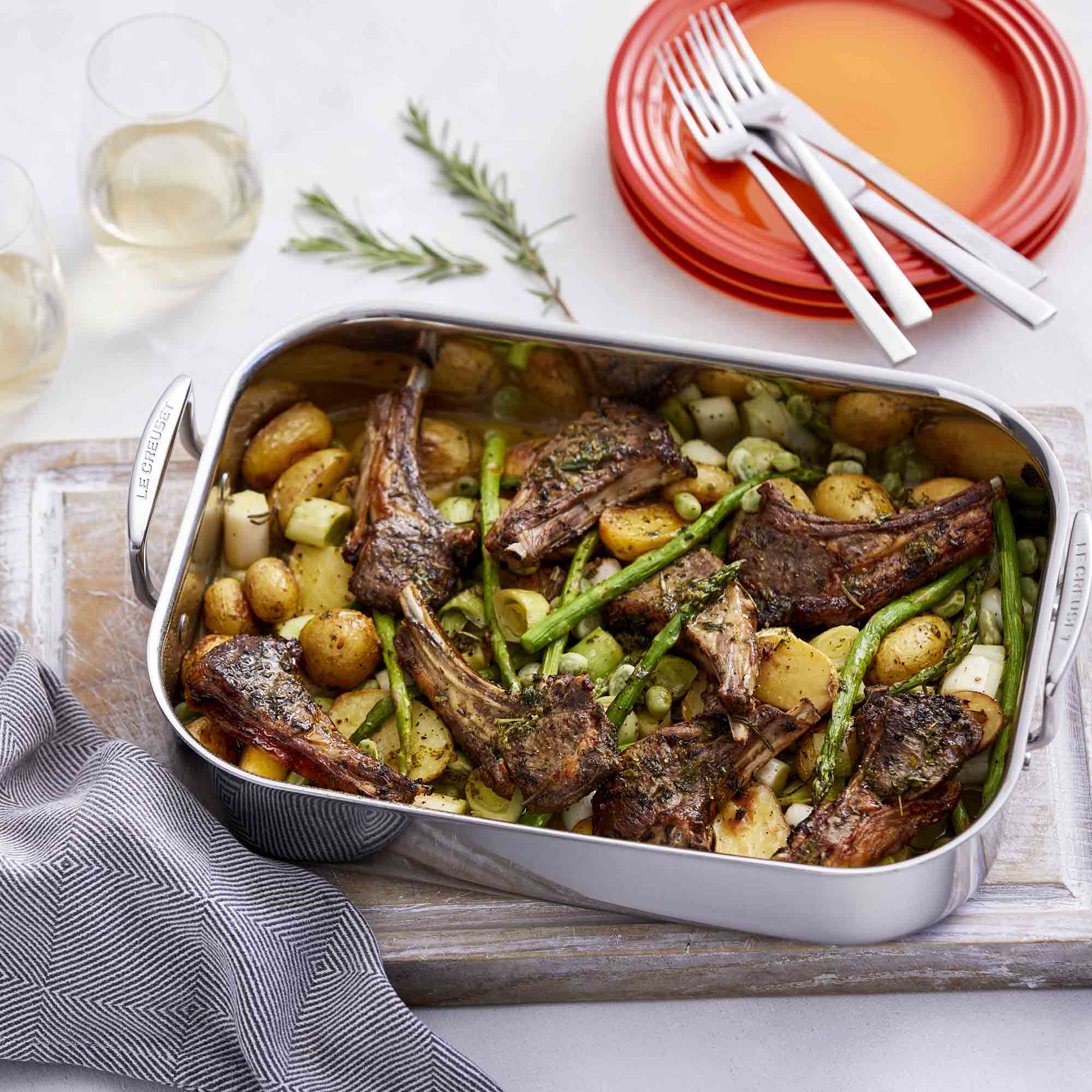 Le Creuset 3-ply Stainless Steel Rectangular Roaster with lamb and vegetable dish on wooden board