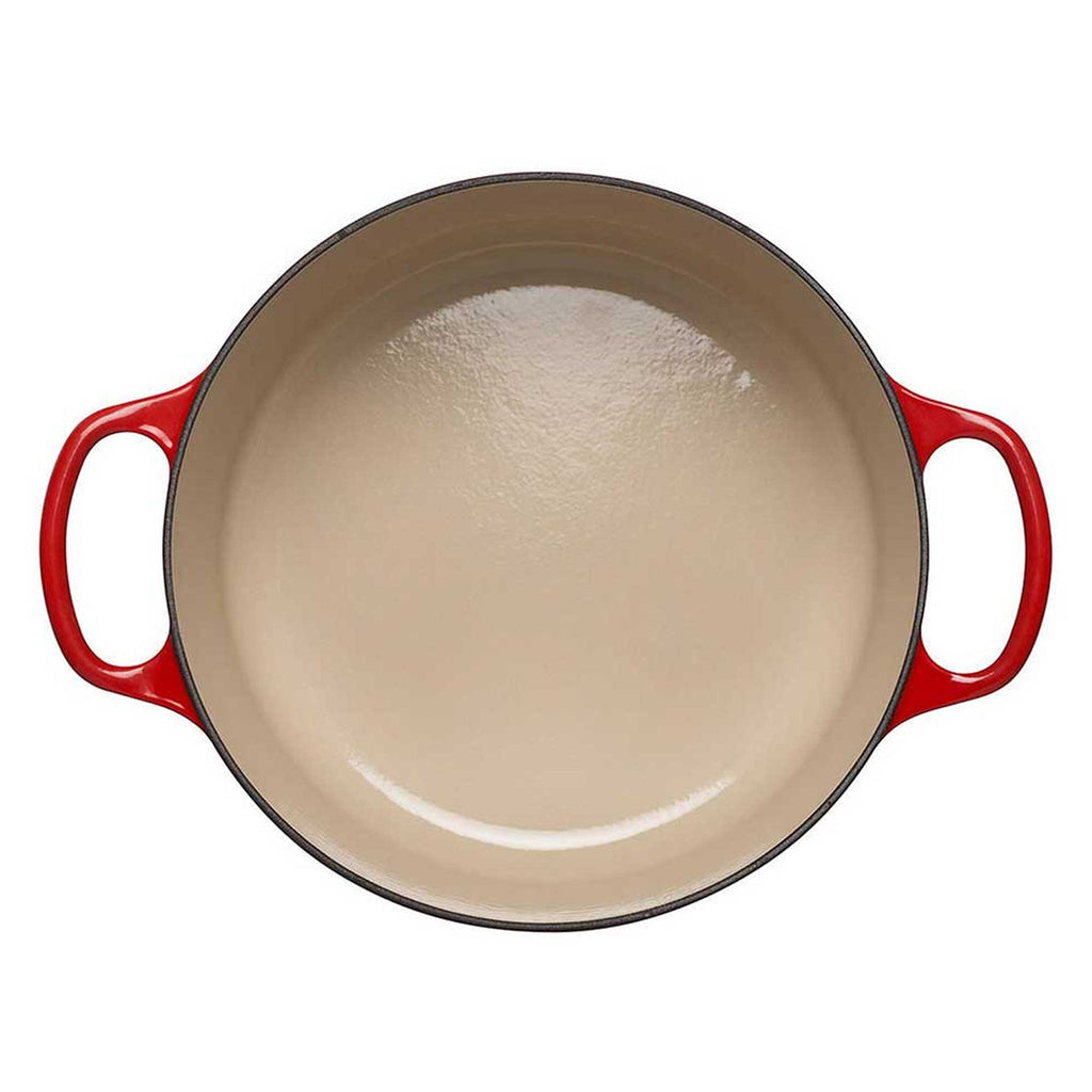 Red cast iron casserole with beige interior on a white background