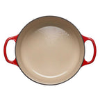 Red cast iron casserole with beige interior on a white background