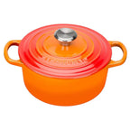 Orange Le Creuset pot with a lid on a white background