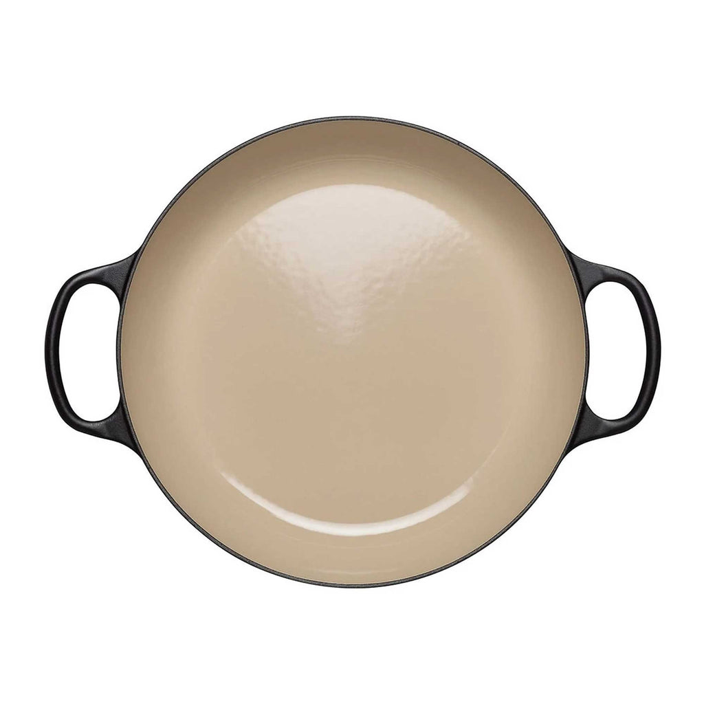 Beige enameled cast iron casserole with black handles on a white background