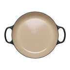 Beige enameled cast iron casserole with black handles on a white background