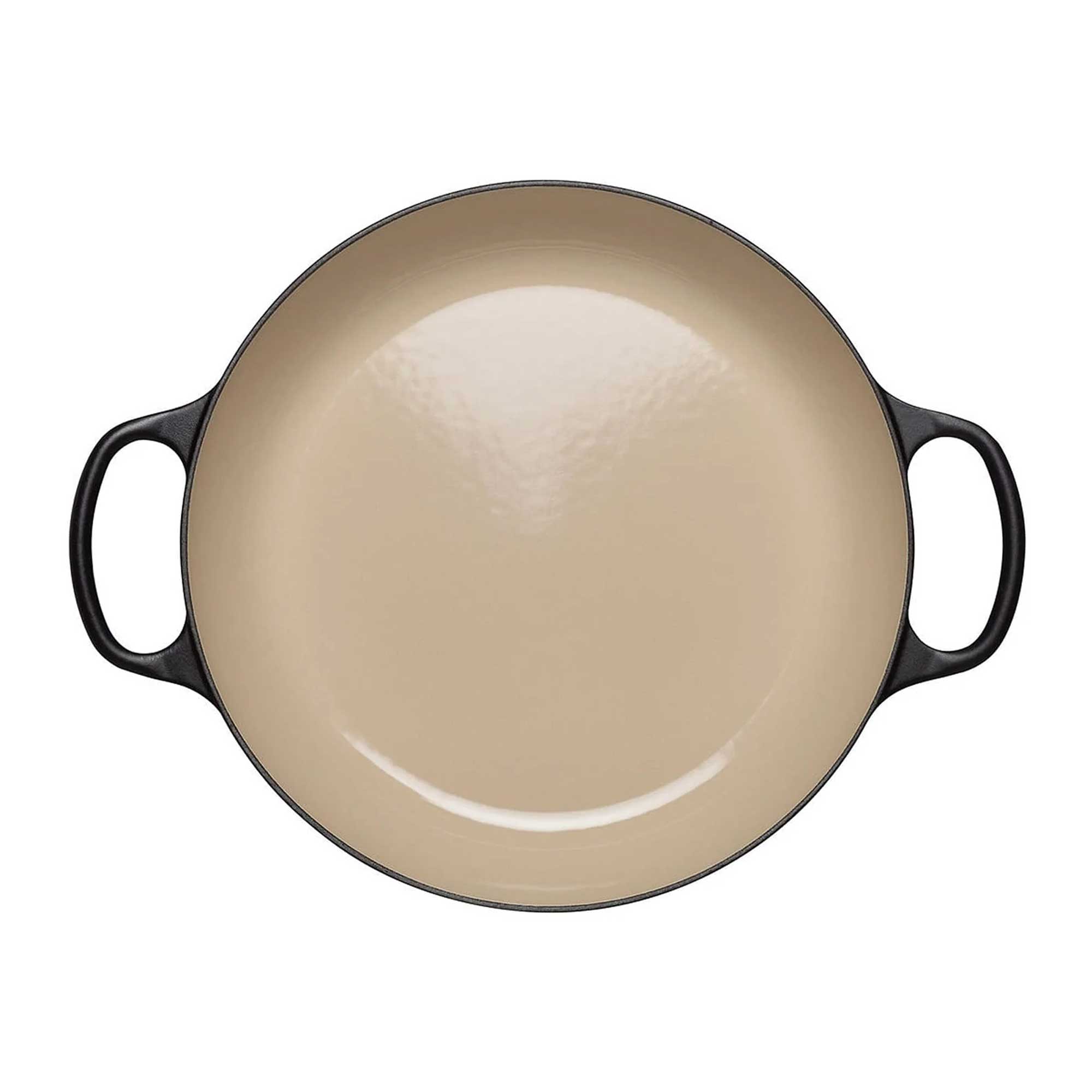 Beige enameled cast iron casserole with black handles on a white background