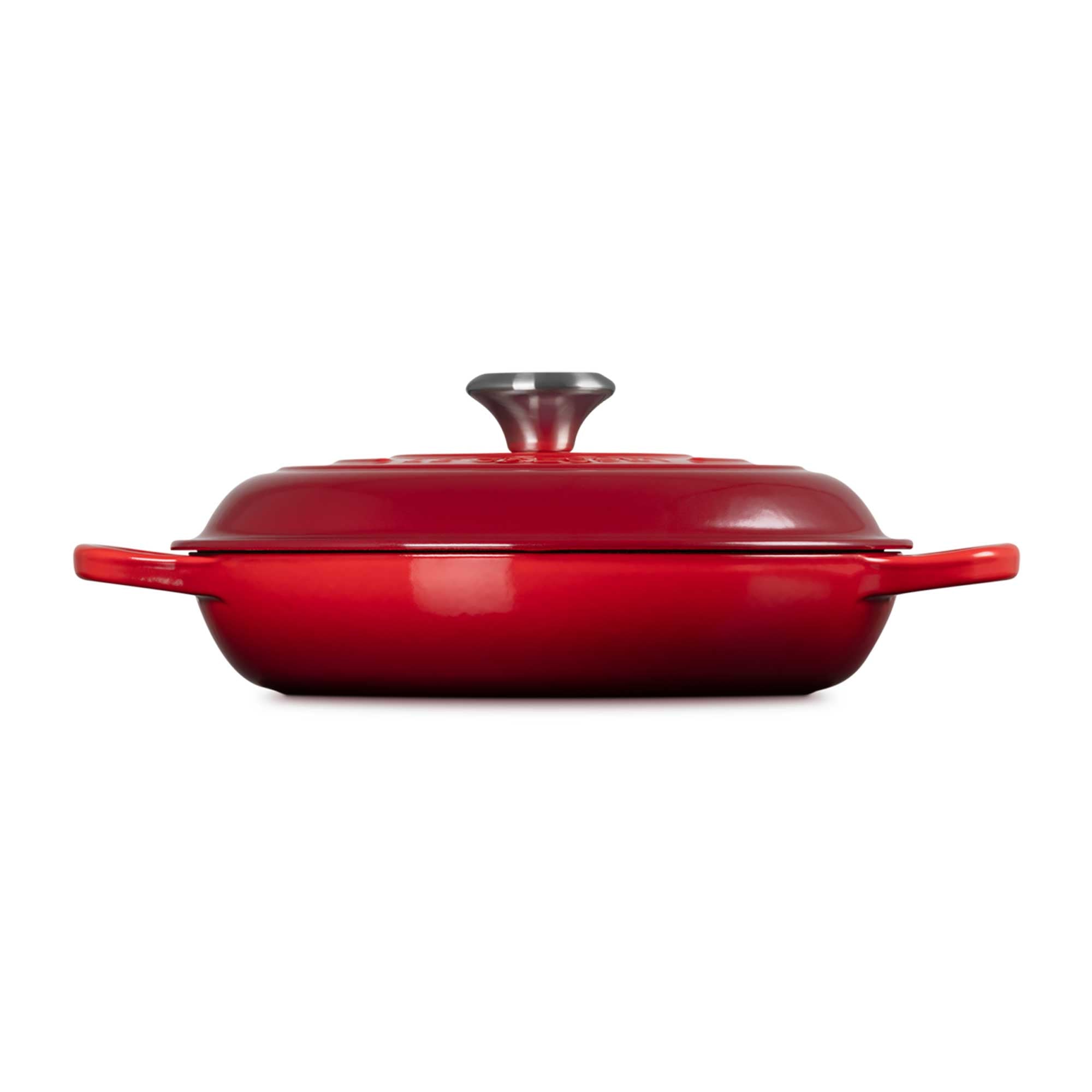 Red enameled cast iron casserole dish with a lid on a white background