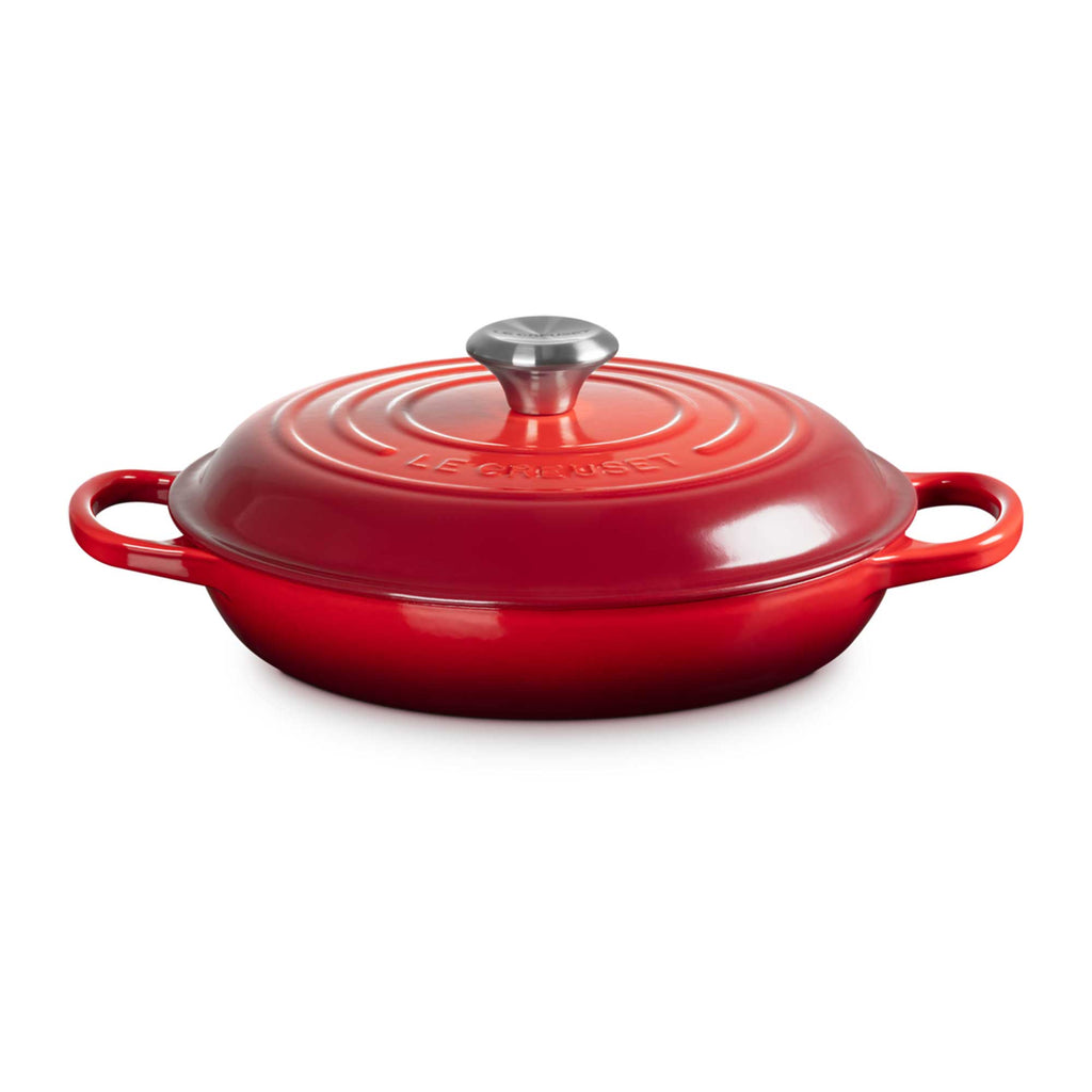 Red enameled cast iron shallow casserole with lid on a white background