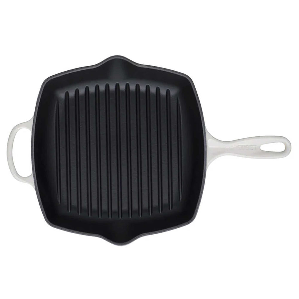 Black cast iron grill pan with white handles on a white background