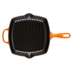 Black cast iron grill pan with orange handles on a white background