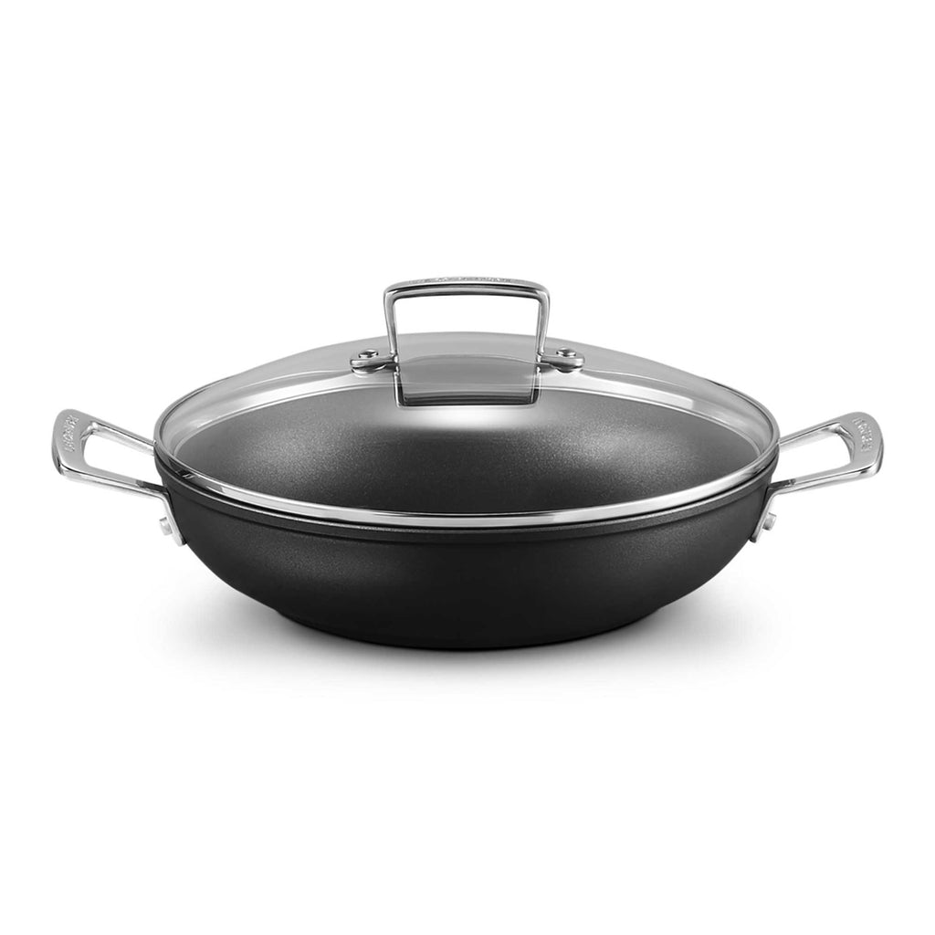 Shallow casserole with clear lid and silver handles on white background