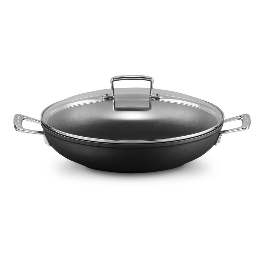 Black shallow casserole with a lid on a white background
