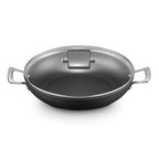 Black shallow casserole with glass lid on a white background