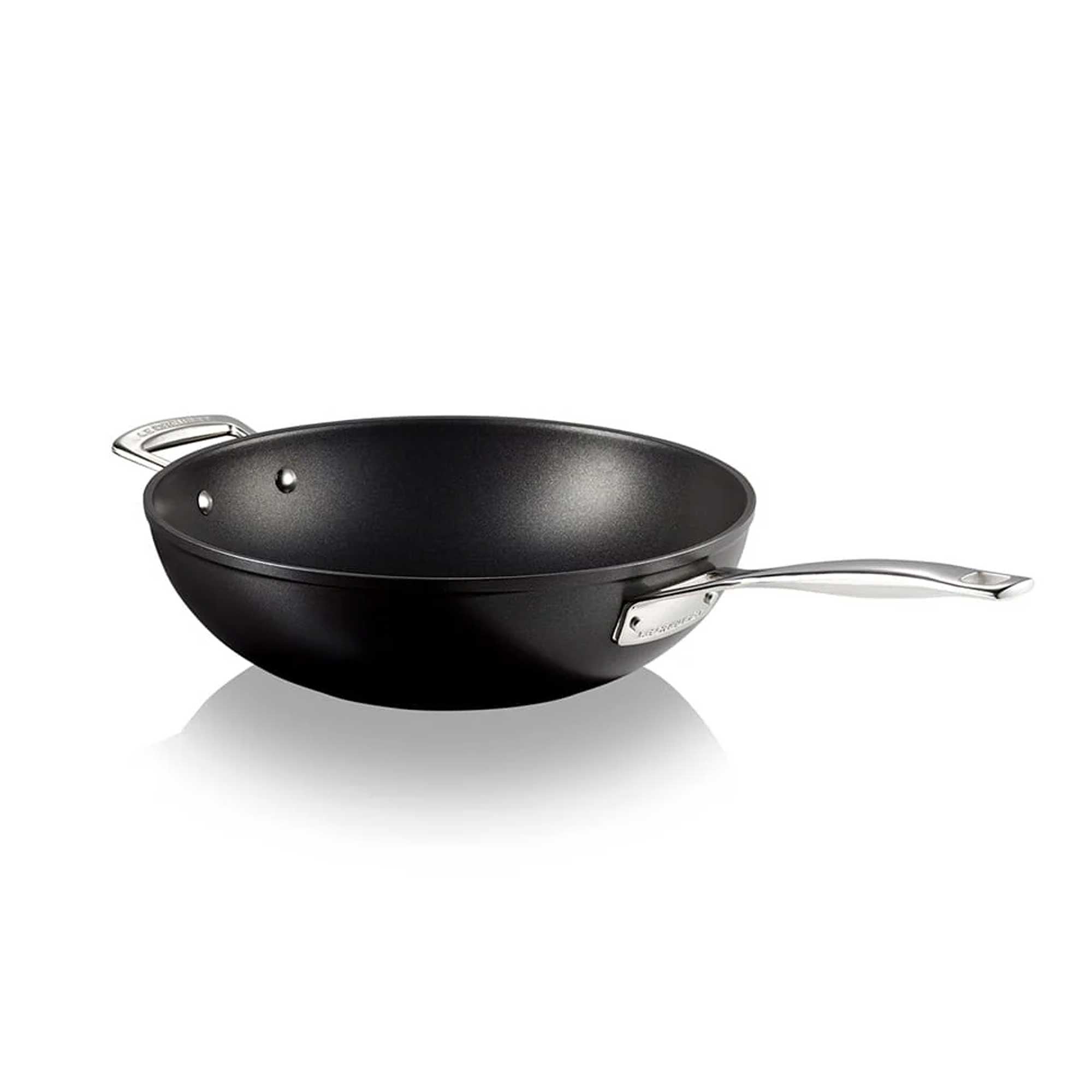 Black stir fry pan with a silver handle on a white background