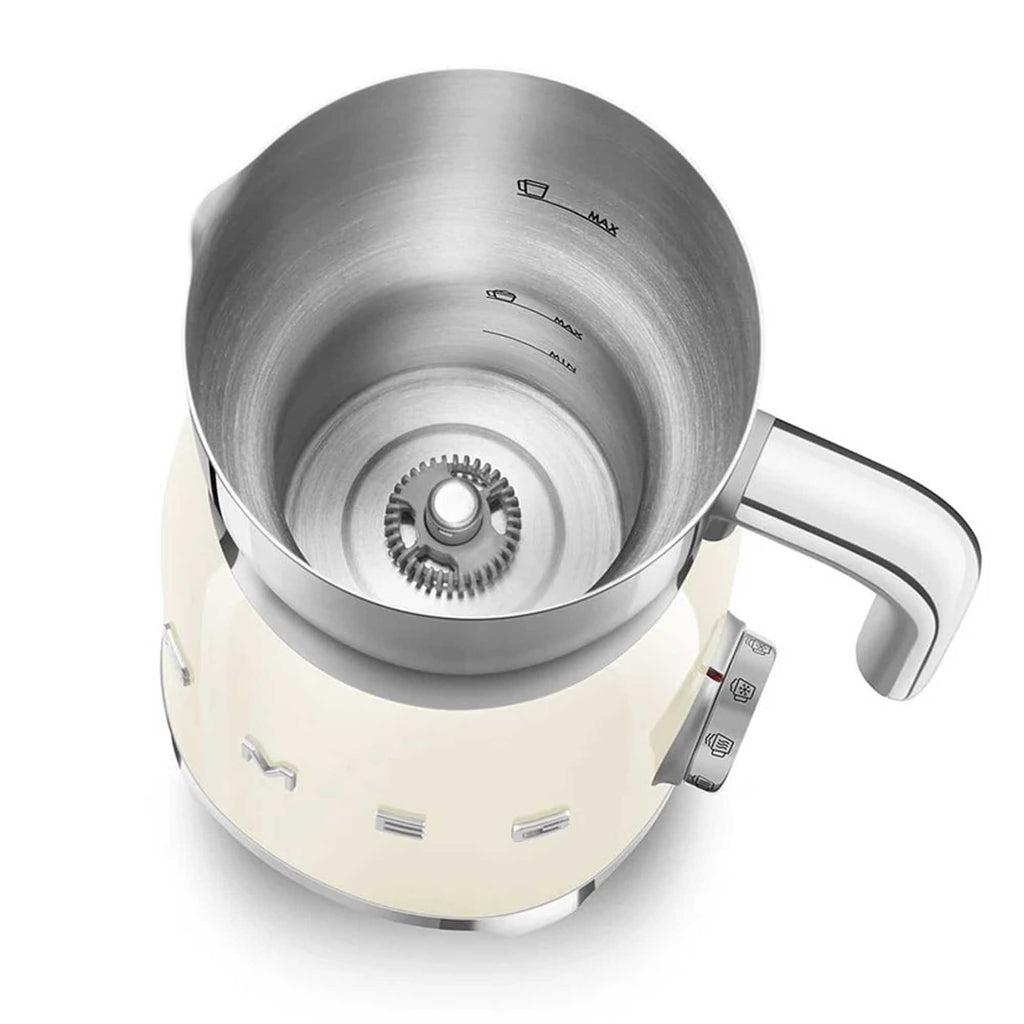 Stainless steel jug of a cream milk frother showing internal measuring lines with a white base on a white background