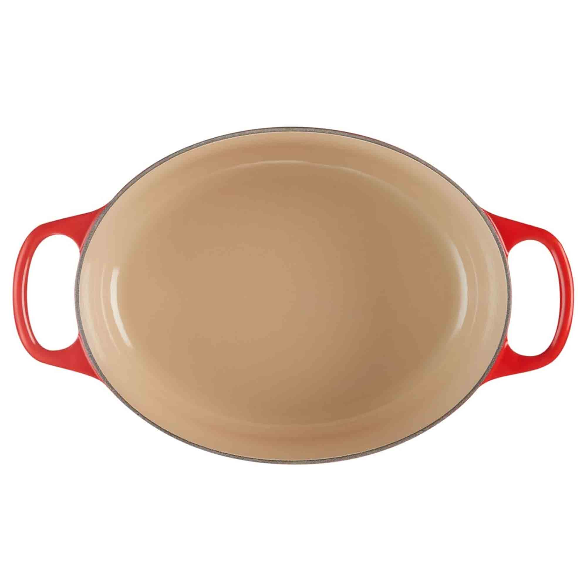 Cerise cast iron oval casserole with beige interior on a white background