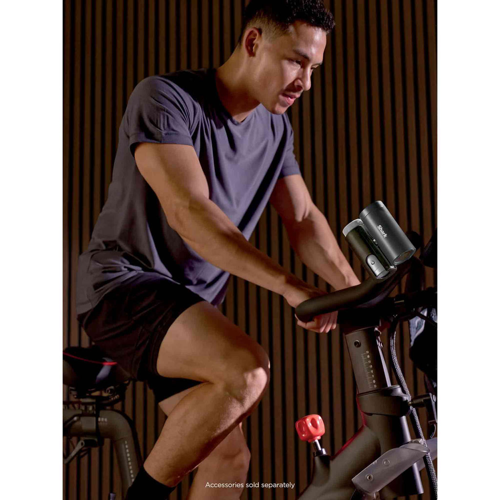 Man exercising on a stationary bike indoors using the Shark ChillPill to keep cool
