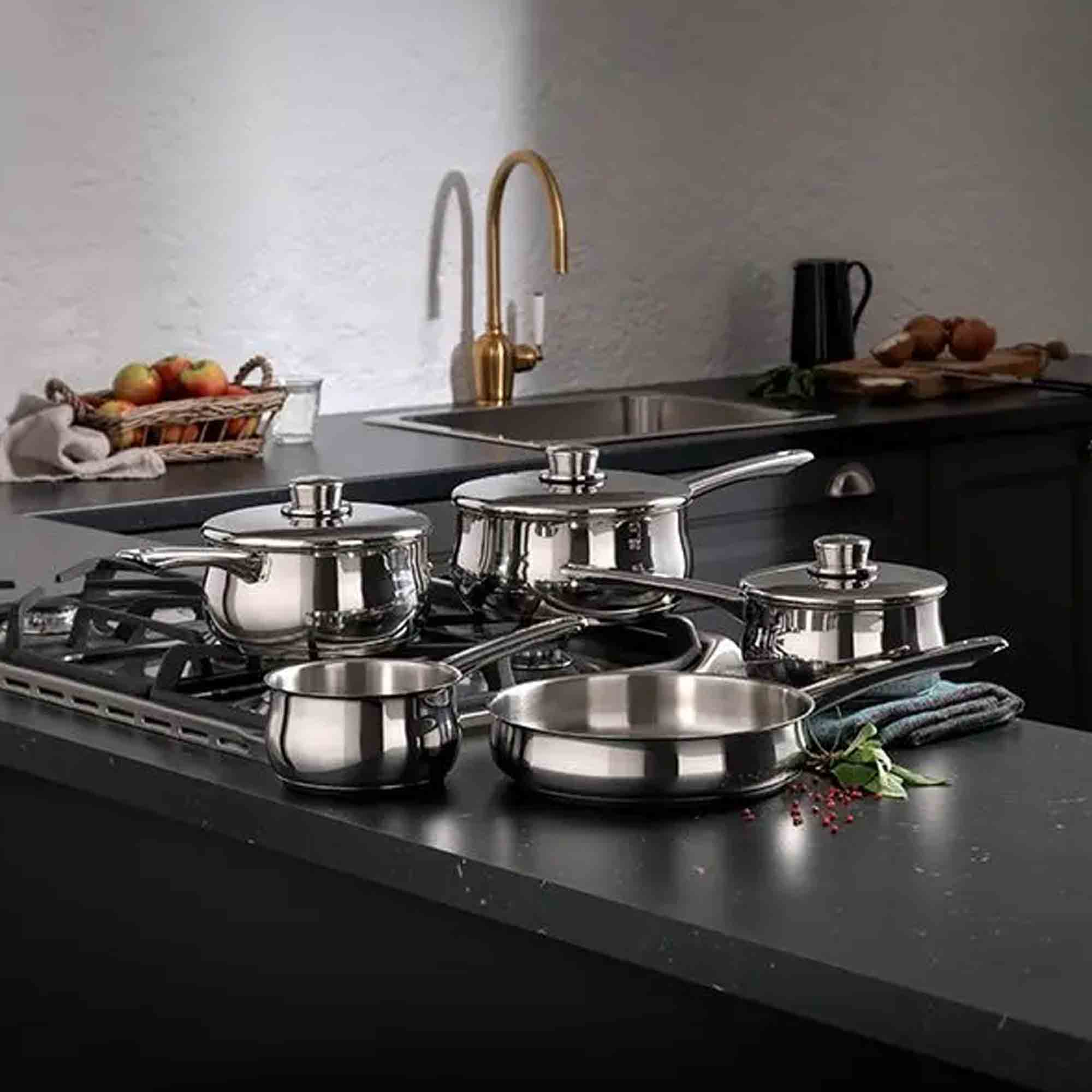 Set of Stellar S1C1B stainless steel cookware on a kitchen counter with a modern kitchen background.