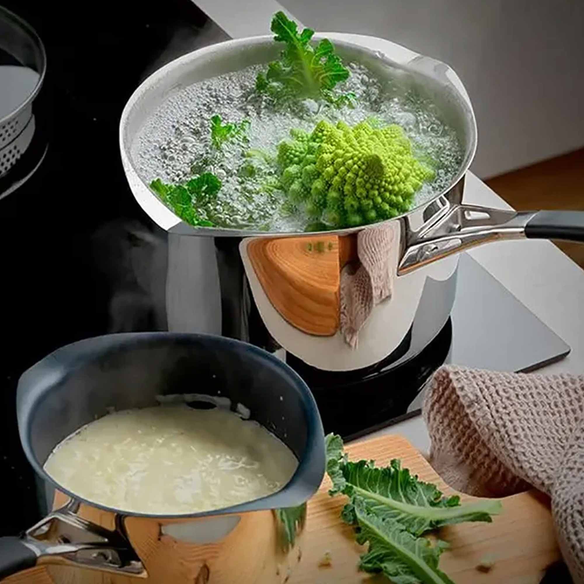 2 silver saucepans cooking a green vegetable and creamy sauce