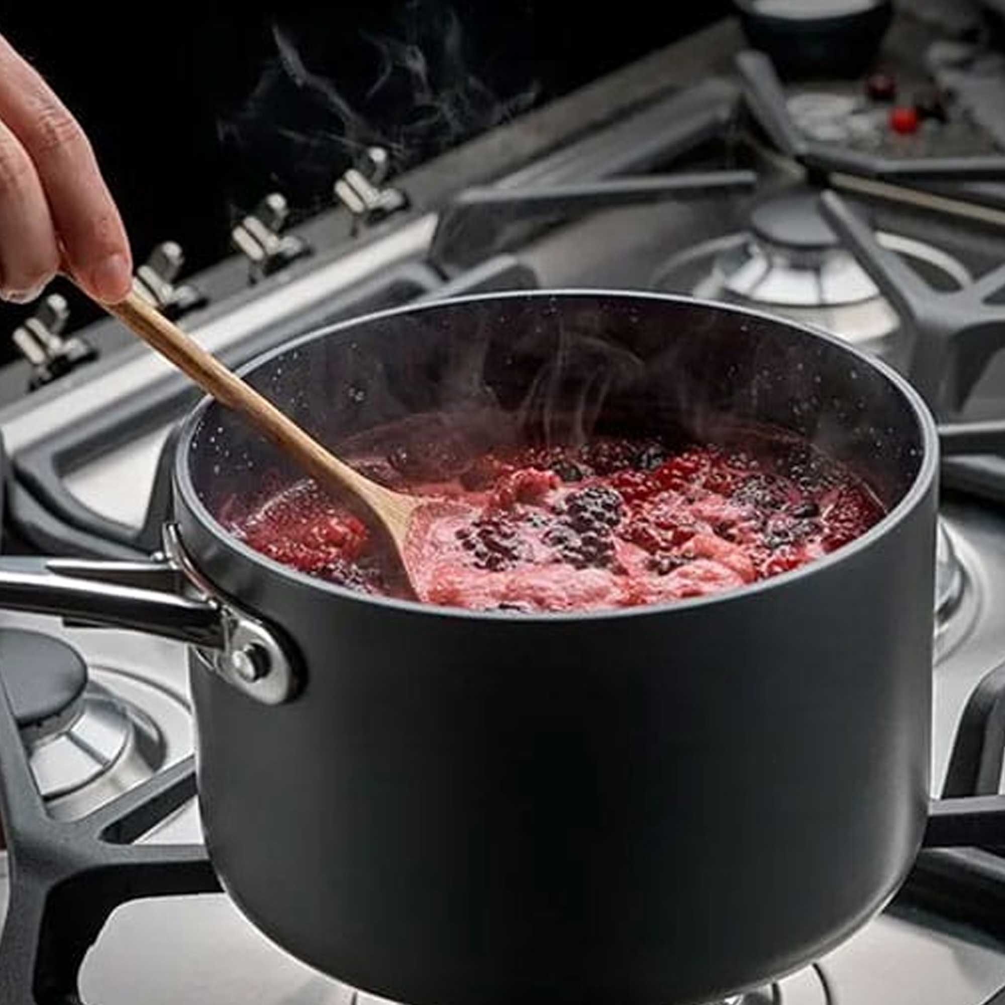 Black saucepan with blackberries and wooden spoon