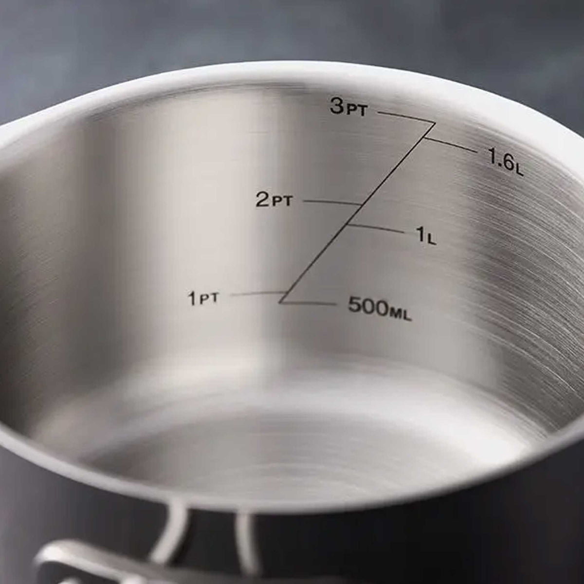 Close-up of the inside of a brushed stainless steel saucepan or pot with printed measurement markings in cups and liters alongside 500ML.
