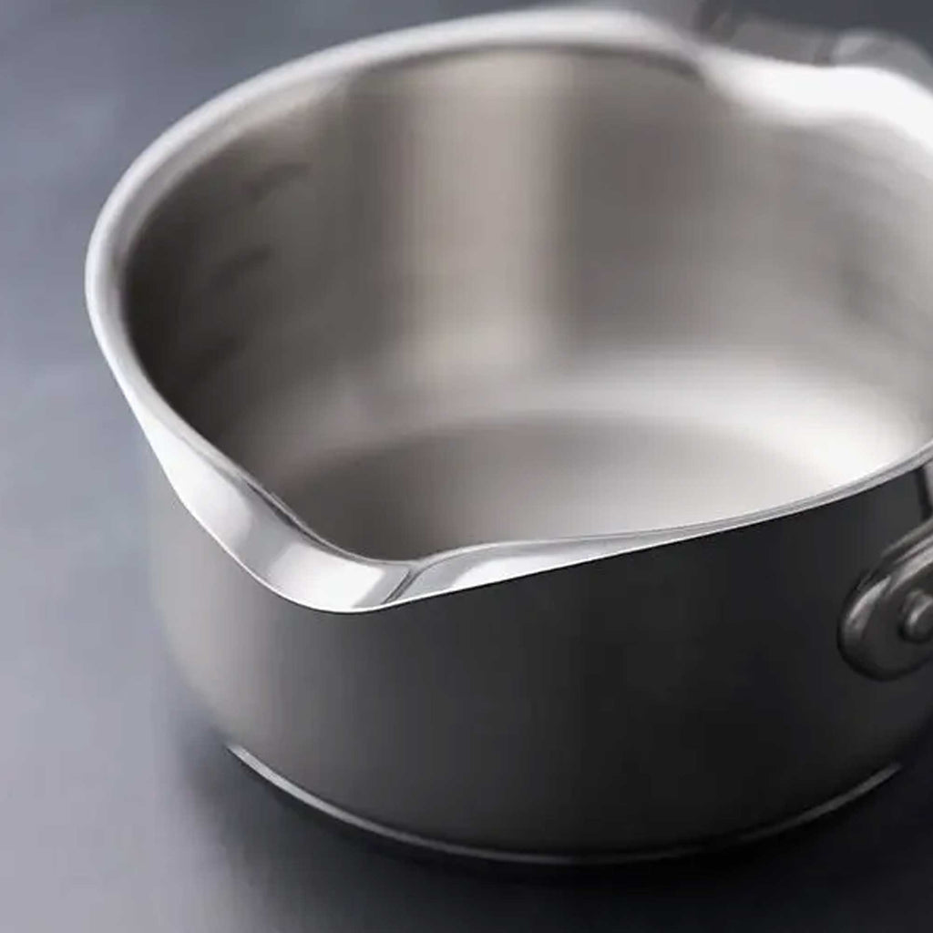 Close-up of a stainless steel saucepan with a polished interior and a dark exterior, resting on a dark gray surface.