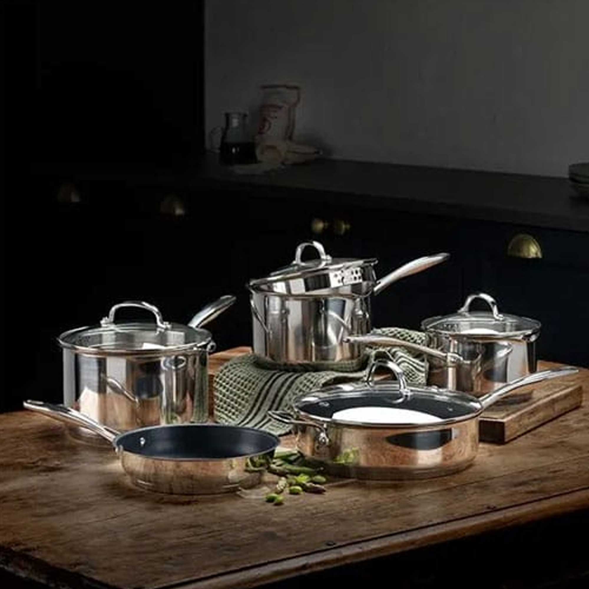 Set of silver saucepans on a wooden surface and chopping board