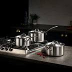 Set of stainless steel cookware on a kitchen stove with a dark background