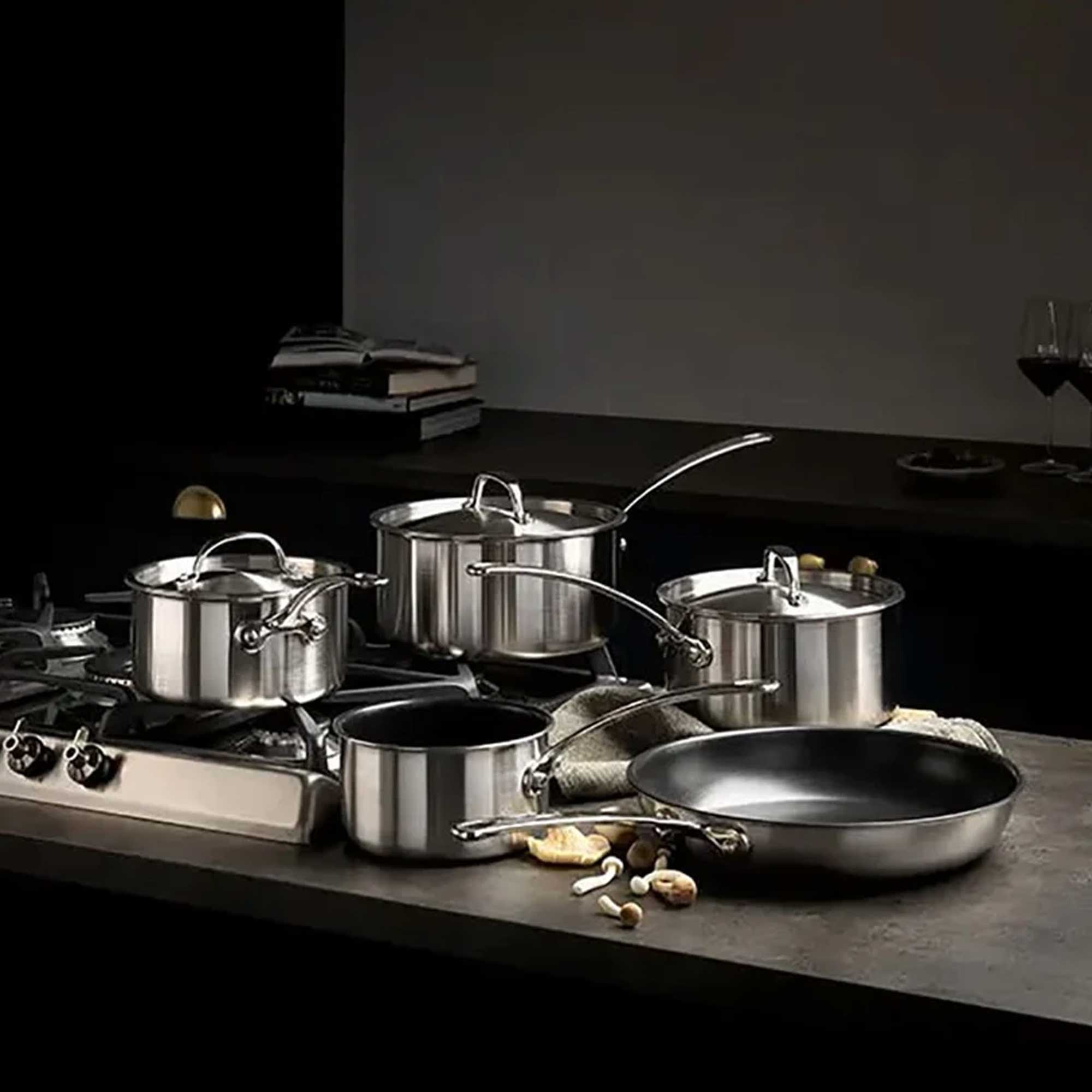 Set of stainless steel cookware on a kitchen counter with a dark background