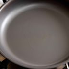 Close-up of the inside of a dark gray non-stick frying pan, showing the textured surface and concentric heating rings.