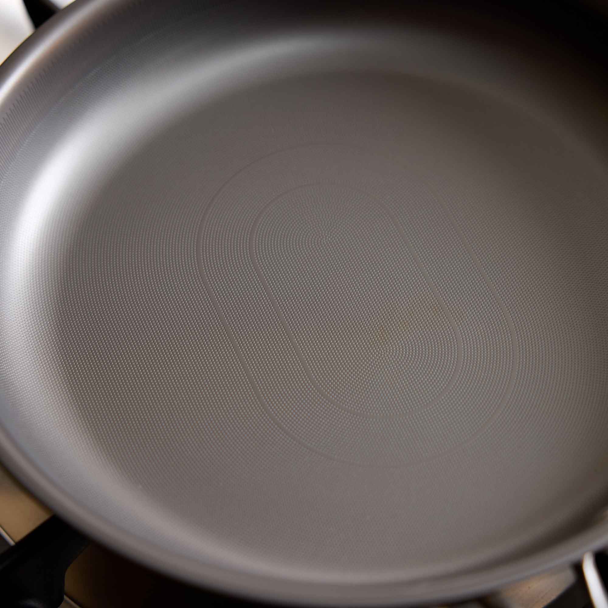 Close-up of the inside of a dark gray non-stick frying pan, showing the textured surface and concentric heating rings.