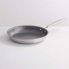 A stainless steel frying pan with a dark gray non-stick interior, shown on a clean white background.
