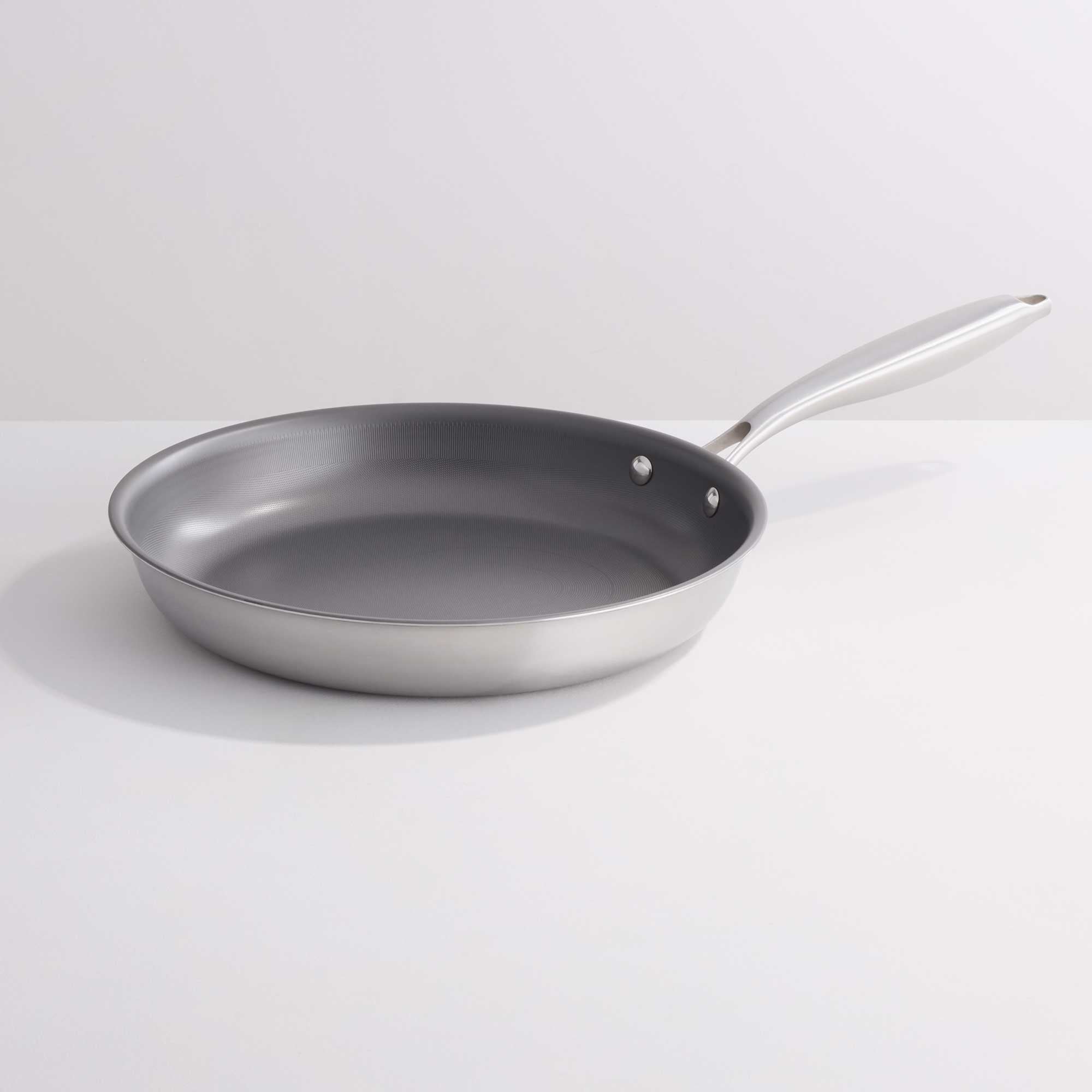 A stainless steel frying pan with a dark gray non-stick interior, shown on a clean white background.