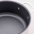 Close-up of a silver saucepan with a dark gray non-stick interior, showing the textured coating and a silver rivet near the rim.