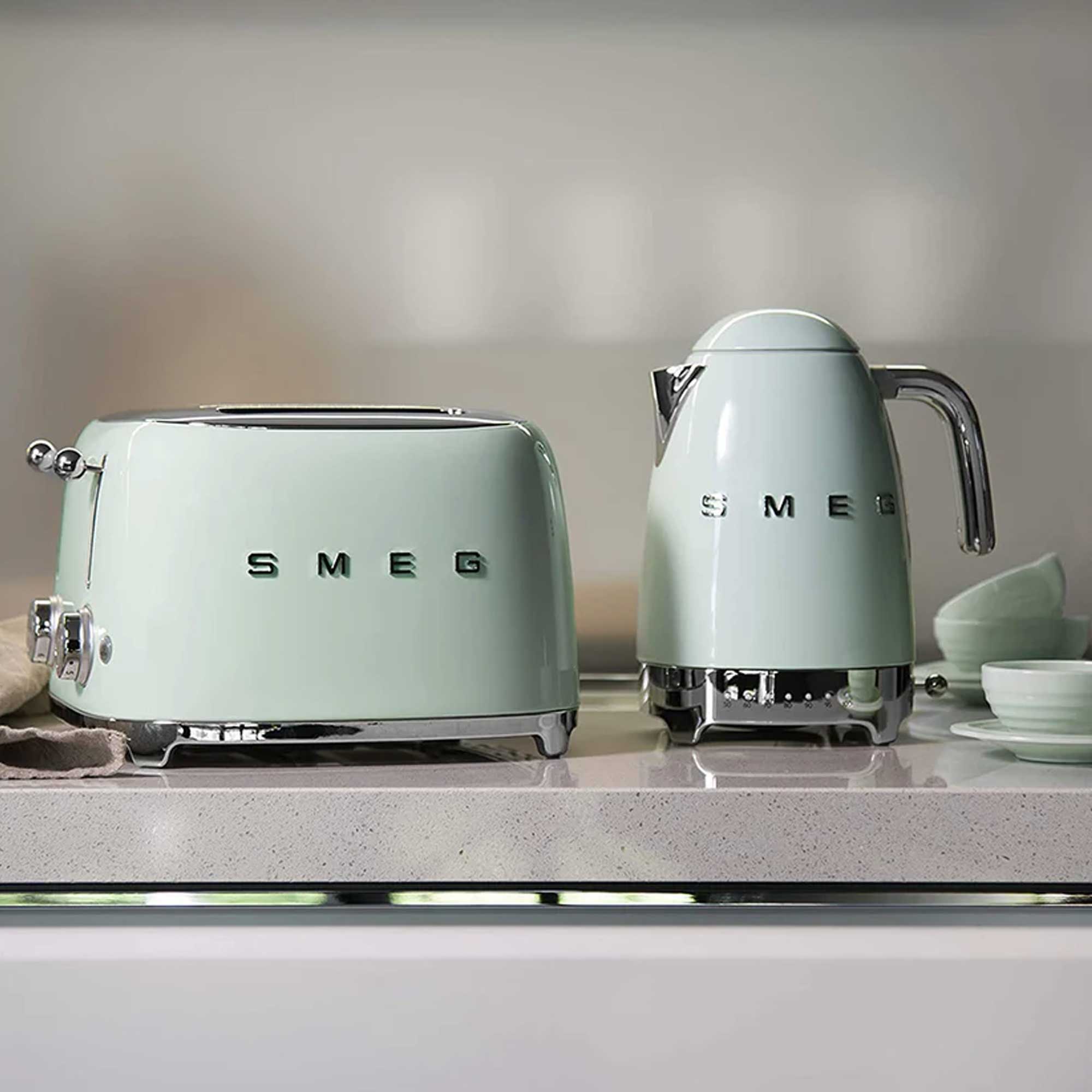 Two pastel green Smeg appliances, a toaster and a kettle, on a kitchen counter.
