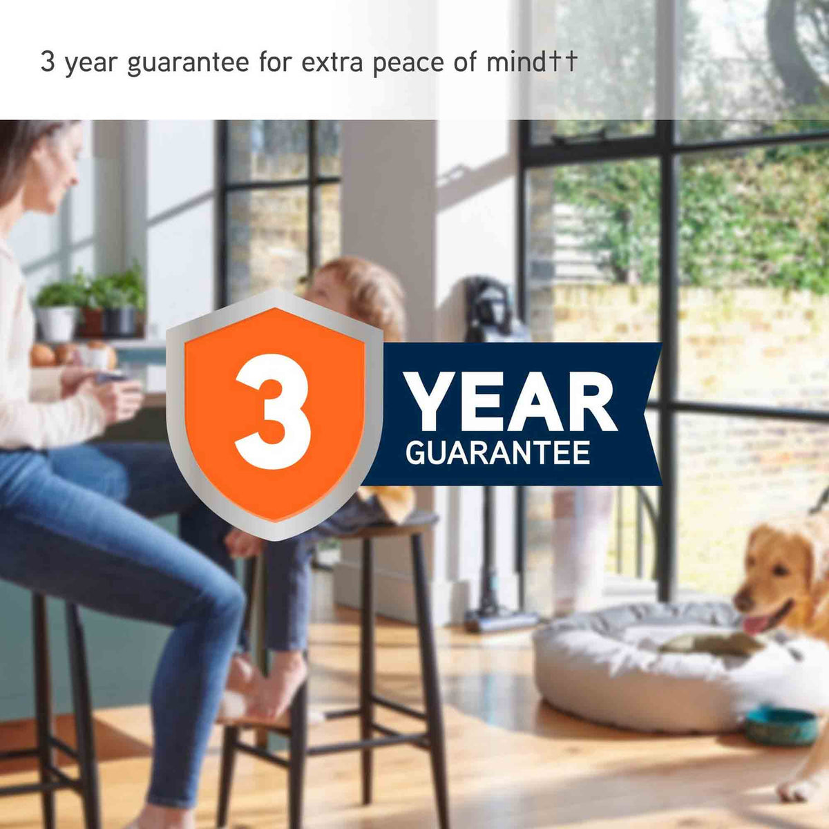A promotional graphic for a 3-year guarantee, featuring a large orange and navy shield icon with the text '3 YEAR GUARANTEE' overlaid on a lifestyle scene of a woman and child sitting on stools in a bright room, with a dog on a cushion nearby.