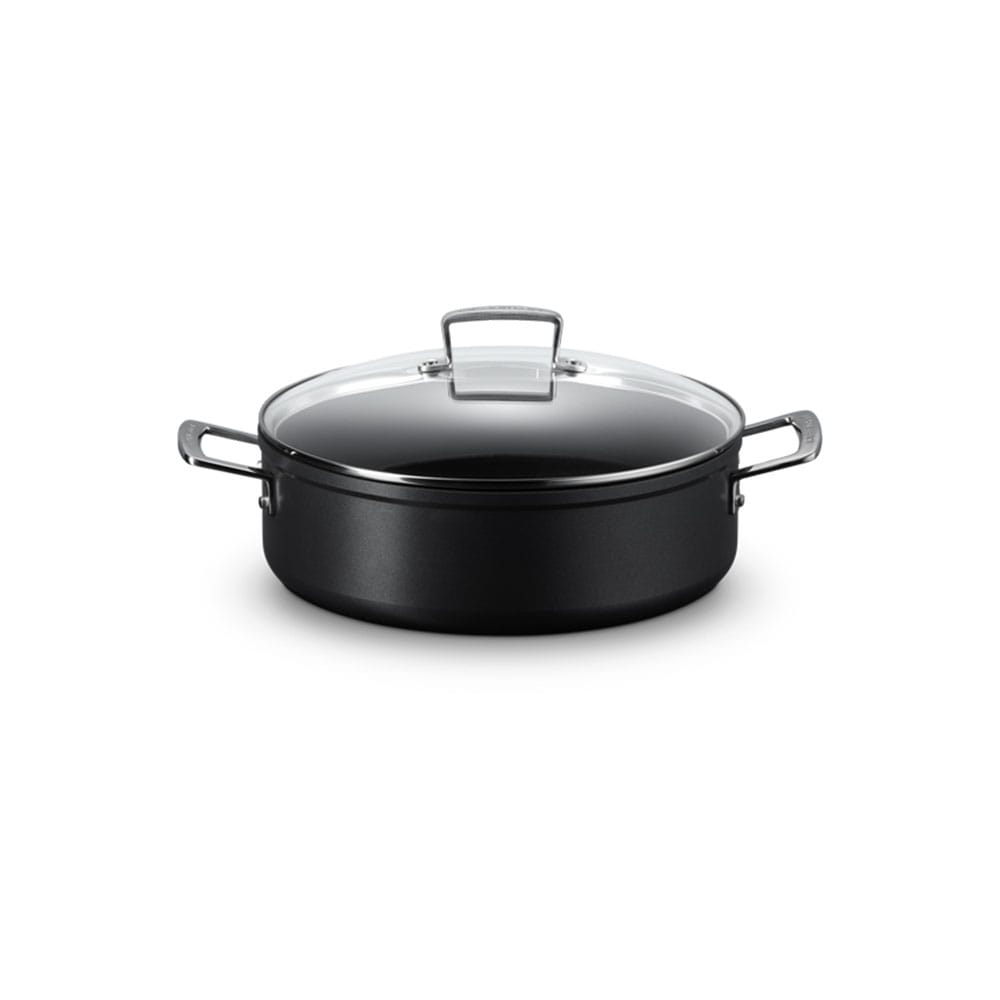Black sauteuse with a clear glass lid on a white background