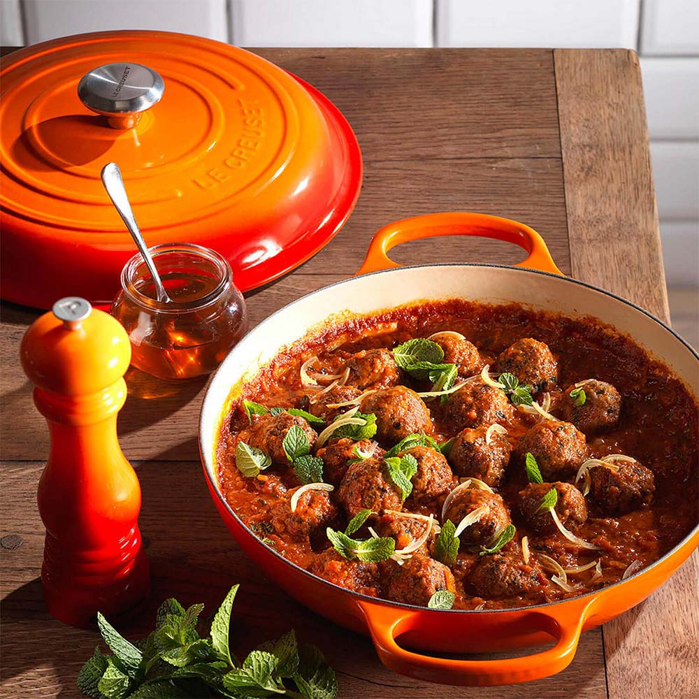 Volcanic Le Creuset dish with meatball dish on a wooden table