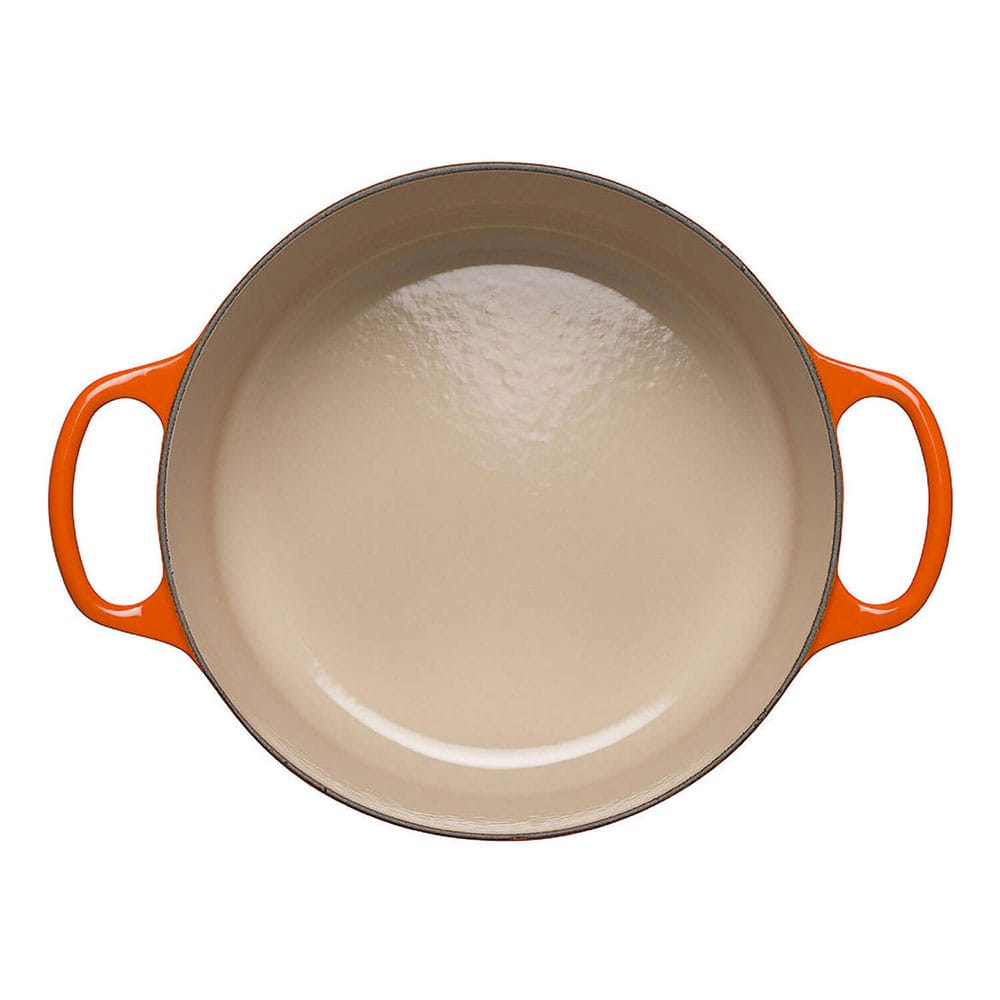 Round volcanic casserole with orange handles on a white background